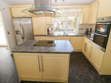 A kitchen with an island, sink, and refrigerator at Serenity in Kilgetty