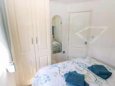A bedroom with a bed, wardrobe, and mirror at Serenity in Kilgetty