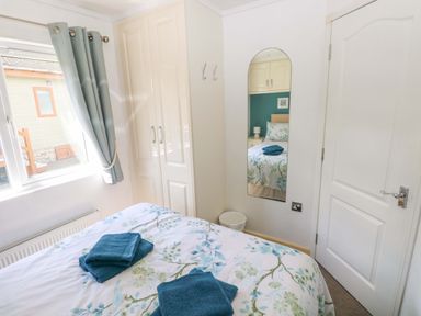 A bedroom with a bed and wardrobe at Serenity in Kilgetty