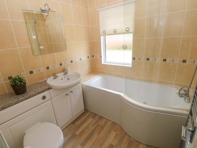 A bathroom with a bath, sink, and toilet at Serenity in Kilgetty