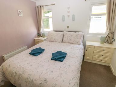 A bedroom with a double bed and bedside table at Serenity in Kilgetty