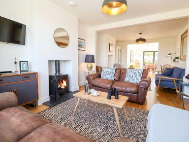 A living room with leather sofas a wood stove and a wooden coffee table at Long View in Southwold