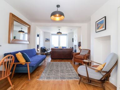 A living room with various chairs and sofas a rug and framed pictures on the wall at Long View in Southwold