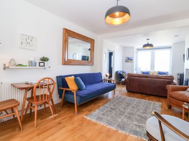 A living room with wooden flooring blue and brown sofas and a wooden table with chairs at Long View in Southwold