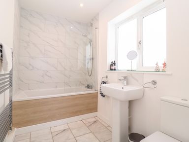 A bathroom with a bathtub shower combination sink toilet and towel rack at Long View in Southwold