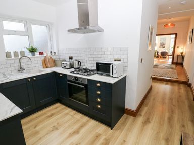 A kitchen with black cabinetry white countertops and subway tile backsplash at 36A Mary Street in Porthcawl