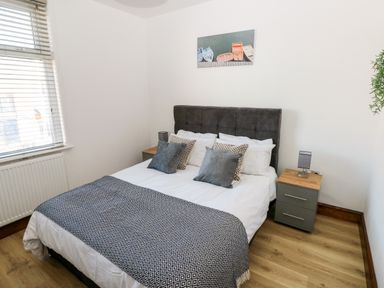 A bedroom with a bed and two bedside tables with lamps at 36A Mary Street in Porthcawl