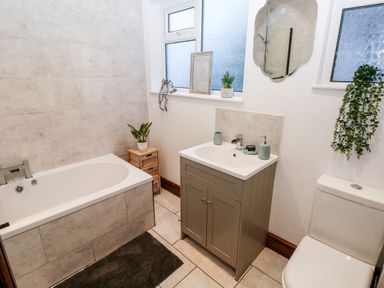 A bathroom with a bathtub sink cabinet toilet and plants at 36A Mary Street in Porthcawl