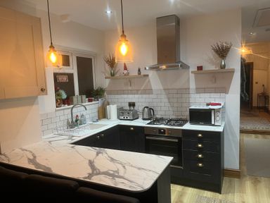 A kitchen with marble countertops a stovetop oven microwave toaster kettle and hanging lights at 36A Mary Street in Porthcawl