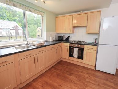 A kitchen with wooden cabinets and a sink at Whitbarrow 24 in Penruddock