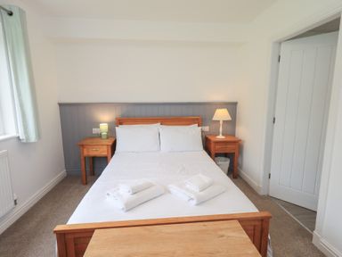 A bedroom with a bed and nightstands at Whitbarrow 24 in Penruddock