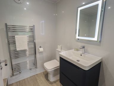A bathroom with a toilet, sink, towel rack, and mirror at Whitbarrow 24 Penruddock