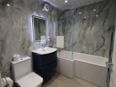 A bathroom with a bathtub, toilet, sink, and mirror at Whitbarrow 24 in Penruddock