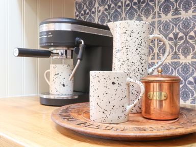 A coffee machine a white speckled mug and jug and a copper container on a wooden tray in a kitchen at The Riblows Cape Cornwall Bollowal near St Just