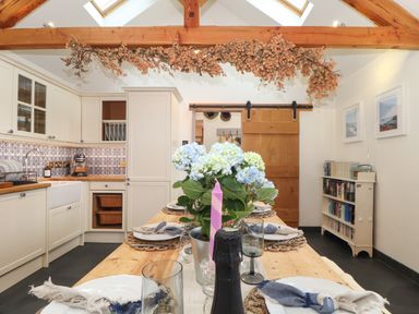 A kitchen with a wooden dining table set with plates glasses and napkins at The Riblows Cape Cornwall Bollowal near St Just