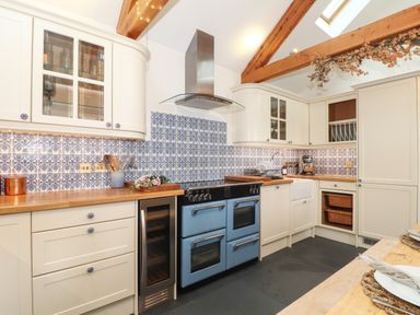 A kitchen with cream cabinets blue patterned tile backsplash and a blue stove at The Riblows Cape Cornwall Bollowal near St Just