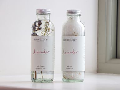 Two bottles of lavender bath products on a white surface near a window