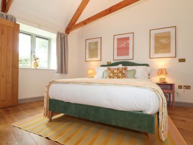 A bedroom with a green bed frame white bedding two bedside tables with lamps and three framed pictures on the wall at The Riblows Cape Cornwall Bollowal near St Just