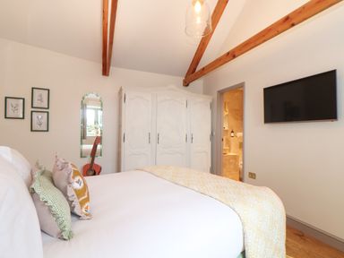 A bedroom with a bed pillows wardrobe wall mirror guitar and a wall mounted television at The Riblows Cape Cornwall Bollowal near St Just