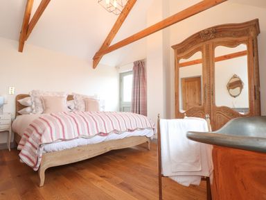 A bedroom with a bed striped quilt wooden wardrobe with mirrors and a towel on a chair at The Riblows Cape Cornwall