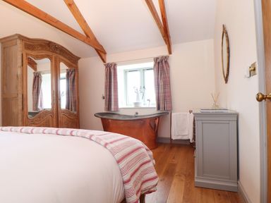 A bedroom with a bed wooden wardrobe copper bathtub and grey dresser at The Riblows Cape Cornwall Bollowal near St Just