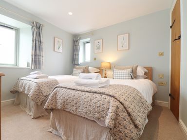 A bedroom with two single beds each with folded towels and patterned bedspreads at The Riblows Cape Cornwall Bollowal near St Just