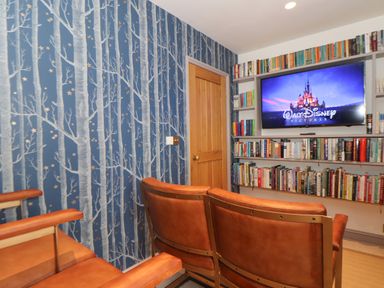 A small home theater room with brown theater seats a television screen and shelves full of books at The Riblows Cape Cornwall in Bollowal near St Just