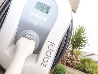 An electric vehicle charging station with a plugged in charging cable outside near plants at The Riblows Cape Cornwall Bollowal near St Just