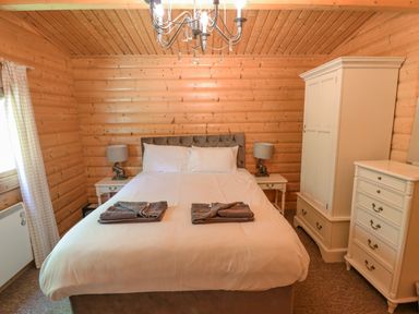 A bedroom with a double bed two bedside tables with lamps a wardrobe and a chest of drawers at 64 Acorn Lodge Kenwick Park in Louth