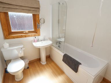 A bathroom with a toilet a pedestal sink and a bathtub with a glass shower screen at 64 Acorn Lodge Kenwick Park Louth