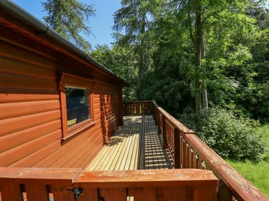 A wooden deck attached to a cabin overlooking a forested area at 64 Acorn Lodge Kenwick Park in Louth