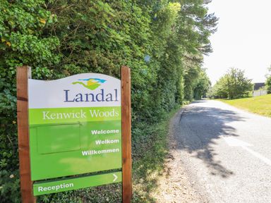 A signboard for Landal Kenwick Woods near a road with trees and grass at 64 Acorn Lodge Kenwick Park in Louth