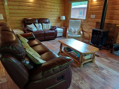A living room with leather sofas a wooden coffee table an armchair and a wood stove at 64 Acorn Lodge Kenwick Park in Louth