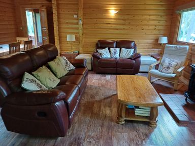 A living room with brown leather sofas a wooden coffee table wooden walls and floor at 64 Acorn Lodge Kenwick Park in Louth