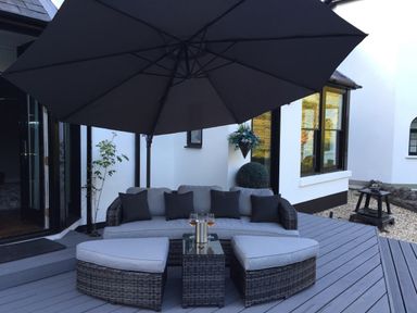 A patio area with a sofa, cushions, an umbrella, and a small table with glasses at Glamorgan House in Cardiff
