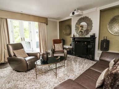 A living room with leather armchairs a sofa a coffee table a fireplace and large windows at Glamorgan House in Cardiff