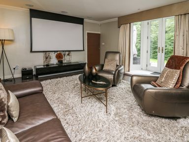 A living room with leather chairs sofa and a projector screen at Glamorgan House Cardiff