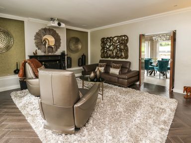 A living room with leather chairs a sofa a round coffee table and decorative wall hangings at Glamorgan House in Cardiff