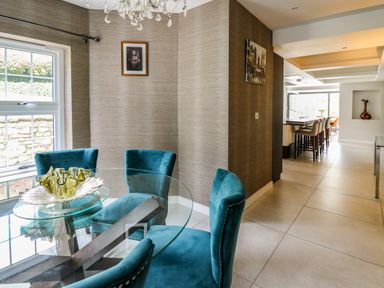 A dining area with a round glass table and blue chairs next to a window at Glamorgan House in Cardiff