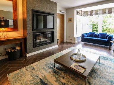 A living room with a blue sofa wooden coffee table and wall mounted TV above a fireplace at Glamorgan House in Cardiff