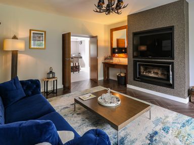 A living room with a blue sofa a wooden coffee table a fireplace and a television at Glamorgan House in Cardiff