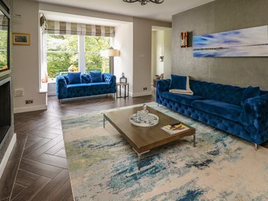 A living room with two blue sofas a wooden coffee table and large window at Glamorgan House in Cardiff