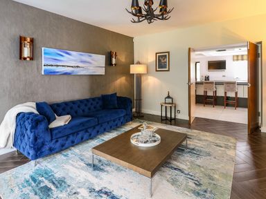 A living room with a blue sofa a wooden coffee table and an open door to a kitchen at Glamorgan House in Cardiff