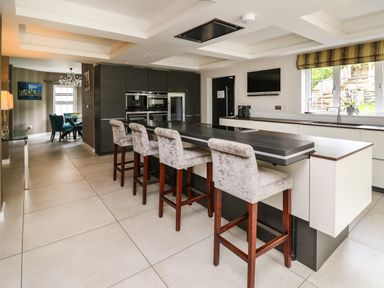 A kitchen with island seating and high chairs near a window at Glamorgan House in Cardiff