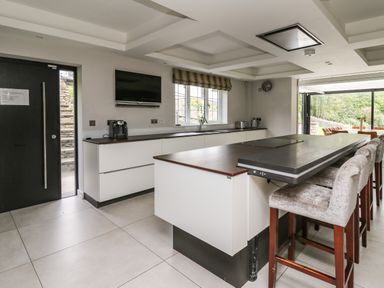 A kitchen with an island and bar stools next to a window and a door at Glamorgan House in Cardiff