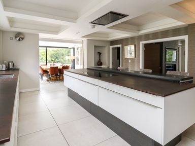 A kitchen with an island and bar stools leading to a dining area with a table and chairs at Glamorgan House in Cardiff