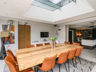 A dining room with a wooden table and brown chairs under a glass ceiling at Glamorgan House in Cardiff