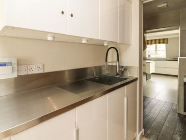 A kitchen area with stainless steel countertop and sink next to a doorway leading to another kitchen space at Glamorgan House in Cardiff