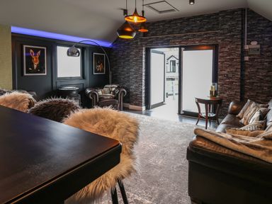 A living room with leather armchairs a sofa a table with candles and artwork on the walls at Glamorgan House Cardiff