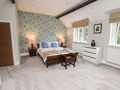 A bedroom with a bed side tables lamps dresser and windows at Glamorgan House in Cardiff